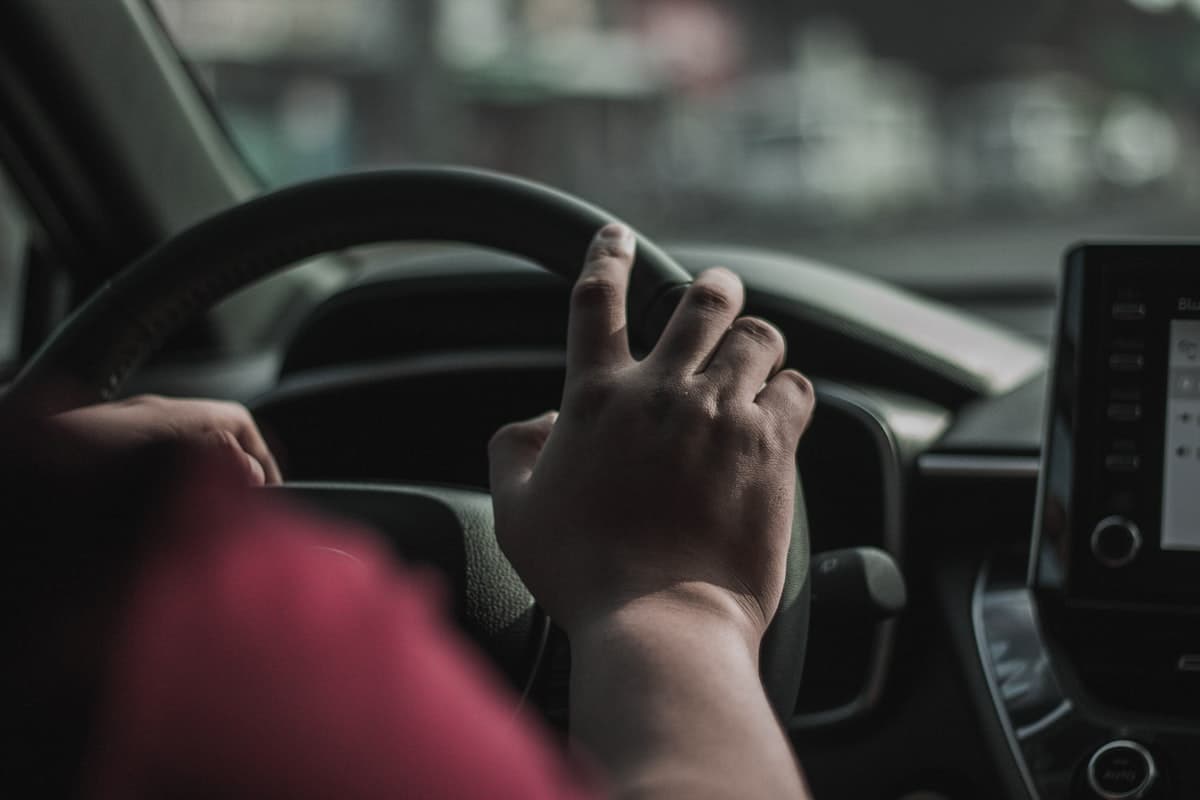 Mãos ao volante de um carro em movimento